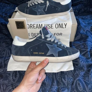 Golden Goose skor - Säljer nu ett par skit snygga blåa mocka sneakers från Golden Goose med vit sula och vita skosnören. Skorna är helt nya oanvända! Box och dust bag medföljer(Allt og)! Storlek 41 men sitter som 42! Skriv vid minsta lilla fråga eller prisförslag! Först till kvarn!!!😊🙌