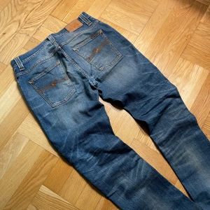 Nudie grim Tim  - Säljer ett par galet feta nudie grim Tim jeans I 9/10 skick. Snyggaste modellen och galen färg med det wash ✨storlekne är 30/34 men kan även passa 31 😄Hör av dig vid minsta fundering. Pris ej hugget i sten och kan sänkas vid en smidiga affär ✅.