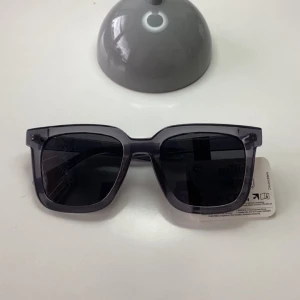 Svarta fyrkantiga solglasögon - Snygga solglasögon med bred, fyrkantig båge i transparent svart plast. Glasen är mörka och ger ett coolt, stilrent intryck. Perfekta för att lyfta din look under soliga dagar. Liknar CHIMI solglasögon 