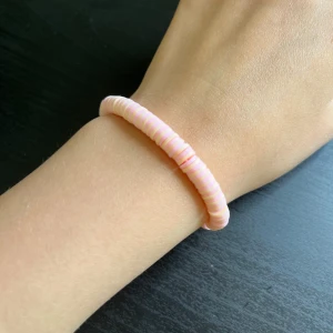 Rosa och gult pärlarmband💝 - Säljer ett sött armband med platta pärlor i rosa och vitt. Armbandet är elastiskt och passar de flesta handleder. Perfekt accessoar för att ge din outfit en färgklick!💝