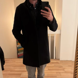 Svart rock från Matinique - Stilren svart rock från Filippa K med klassisk krage och dold knäppning. Jackan har lång ärm och rak passform, perfekt för en clean och tidlös look. Passar lika bra till jeans som till kostymbyxor. Size large och denna skönhet är perfekt till alla typer av stilar… Nypris är 5500:- och den är använd 3 gånger endast.