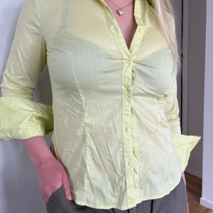 Ljusgrön skjorta med knappar - Säljer en ljusgrön skjorta med lång ärm och klassisk krage. Skjortan har knäppning framtill och är i ett tunt, lätt material som känns fräscht till våren eller sommaren. Passformen är normal och skjortan är enkel att styla till olika outfits.