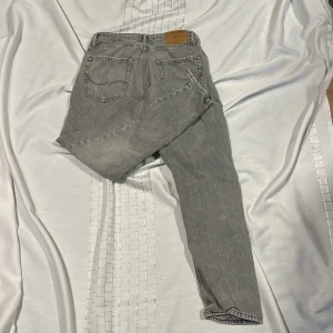 Grå jeans från Jack & Jones - Säljer ett par grå jeans från Jack & Jones med klassisk femficksdesign och raka ben. Jeansen har normal passform och är tillverkade i denim med snygg tvättad look. Perfekta för en avslappnad stil. Modell loose och använda inte så mycket går att pruta.