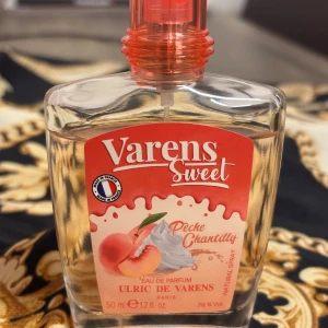 Varens Sweet Peche Chantilly Eau de Parfum - En söt parfym med doft av persika och grädde från Ulric de Varens. Flaskan är rektangulär med rundade kanter, genomskinlig med ljusrosa vätska och har ett rosa lock. En feminin doft från franska Ulric de Varens. Denna Eau de Flaskan innehåller 50 ml mängd enligt bild.  Prisförhandla gärna! Köptes i höstas och förvarats i garderoben. 