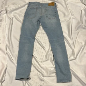 Ljusblå jeans från Jack & Jones - Säljer ett par ljusblå jeans från Jack & Jones med klassisk femficksdesign och normal passform. Jeansen har dragkedjegylf och raka ben. Perfekta för en avslappnad stil. Inga smutsigt eller hål helt äkta helt nya går att pruta.