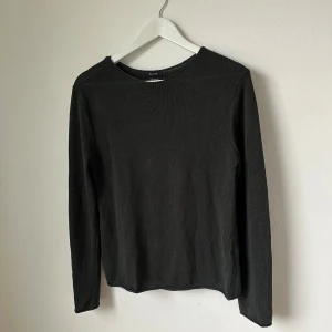 Mörkgrön långärmad tröja från Massimo Dutti - En mörkgrön, långärmad tröja från Massimo Dutti i 100% bomull. Tröjan har en enkel och stilren design med rund halsringning och ribbad struktur. Perfekt för lager-på-lager eller som basplagg i garderoben. Artnr: Ö255