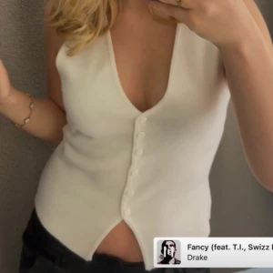 Gina vit stickad väst med knappar - Snygg vit stickad väst med v-ringning och knäppning framtill. Säljer då den inte riktigt passar min smak längre. Jätte fin och perfekt till vardagen! 🩷