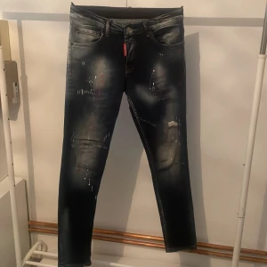 Marin blåa från Dsquared2 - Snygga svarta jeans från Dsquared2 med coola slitningar och färgstänk. De har en klassisk femficksdesign och en röd etikett vid gylfen. Perfekta för en trendig look.