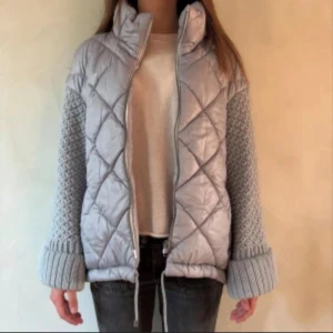 Ljusgrå quiltad jacka med stickade ärmar - SNYGGASTE vår eller höstjackan!!! Så cool och unik och sitter så fint på!! Grå/ljusblå. Quiltat mönster framtill och bak, samt stickade ärmar och muddar. Jackan har hög krage, dragkedja och två fickor med dragkedja. Sista bilden är min, resten är lånade! Skriv vid frågor eller köp direkt☺️