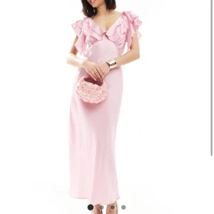 Ljusrosa långklänning med volang - Säljer en ljusrosa långklänning med v-ringning och volangdetaljer upptill. Oanvänd