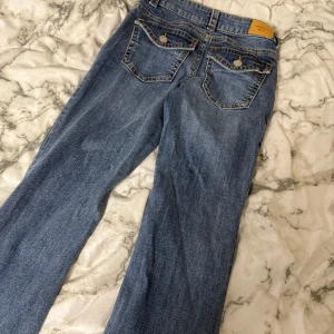 Blå bootcut jeans från Perfect Jeans - Säljer ett par klassiska blå bootcut jeans från Perfect Jeans. Jeansen har normal passform, fem fickor och snygga detaljer med knappar och dragkedja. Perfekta till vardagslooken och passar till det mesta.