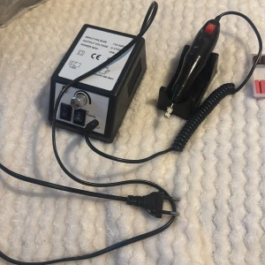 Elektrisk nagelfil med tillbehör - Elektrisk nagelfil med svart handstycke och tillhörande kontrollenhet. Medföljer flera sliphuvuden och slipband i röd och silver färg. Perfekt för att forma och släta ut naglar. Utrustad med strömbrytare och hastighetsreglage.( priset kan diskuteras) ❤️
