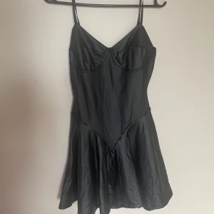Svart satin klänning med smala axelband - Säljer en svart kortklänning i satin med smala axelband och markerad byst. Klänningen har en lätt utsvängd kjol och en stilren, minimalistisk design. Perfekt för dig som gillar en enkel men snygg look. Axelbanden går att ställa in i den storlek man vill ha🖤