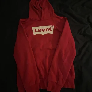Röd hoodie från Levi's - Säljer en riktigt fet röd hoodie från Levi's med klassisk vit logga på bröstet. Tröjan är riktigt fräsch och inga defekter. Riktigt bra skick, o riktigt clean och snygg färg! Säljer den då jag vuxit ur den. Vid några funderingar eller frågor angående priset, skicka ett pm.