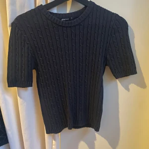 Mörkblå stickad topp från Gina Tricot -  mörkblå stickad topp från Gina Tricot med korta ärmar och rund halsringning. 