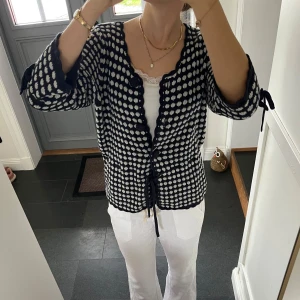 Blå stickad kofta  - Trekvartsärmad blå/vit mönstrad kofta med snörning från Rosebud i storlek M, skulle säga att den även passar S. Fint skick. Använd gärna köp nu!