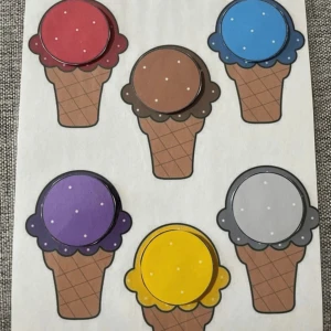 Färgglada glasskort i kartong - Säljer ett set med färgglada glasskort i kartong, perfekta för lek eller pedagogiska aktiviteter. Glassarna har olika färger som röd, blå, brun, lila, gul, grå, beige, grön, orange, rosa, vit och svart. Delarna fästs med kardborreband.