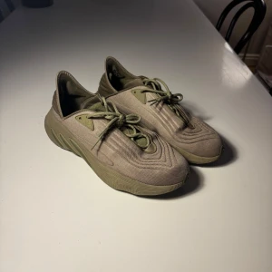 Beige sneakers i Yeezy-stil - Säljer ett par beige sneakers i Yeezy-stil från adidas med unika vågformade detaljer och tjock sula. Skorna har snörning och är tillverkade i syntetmaterial. Perfekta för dig som gillar streetwear och vill sticka ut med en modern look.