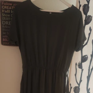 Mörkgrön klänning med knytband i midjan - Säljer en enkel och stilren mörkgrön klänning med korta ärmar och rund halsringning. Klänningen har ett knytband i midjan som ger en fin passform och faller mjukt ner mot benen. Perfekt för en avslappnad och snygg look.