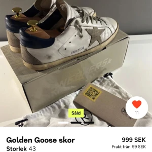 Golden Goose sneakers med stjärndetalj - Säljer ett par vita Golden Goose sneakers med grå stjärna på sidan och mörkblå häl. Skorna har snörning och gulddetaljer på hälen. Snygg vintage-look och levereras med originalkartong och dustbag.