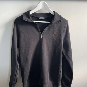  Polo Ralph Lauren zip  - Säljer en svart långärmad tröja från Polo Ralph Lauren med halv dragkedja och röd broderad logga på bröstet. Perfekt för en stilren och avslappnad look. Klassisk passform och mjukt material. OBS!! Priset kan diskuteras