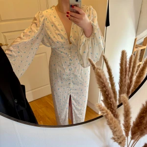 Vit långklänning med blå blommor från Adoore - Supersöt långklänning från Adoore i vit med små blå blommor. Säljes då jag inte fått användning för den.  Aldrig använd, alla lappar finns kvar🥰Liten i storlek!