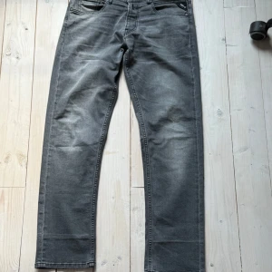 Grå jeans Replay Grover - Säljer ett par grå jeans från Replay, modell Grover. Ett väldigt bra pris för dessa fina jeansen. Storleken är 31.  Klassisk femficksdesign med svarta detaljer och logga på fickan. Jeansen har raka ben och normal passform, perfekta för en stilren vardagslook.