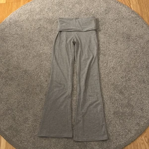 Grå yoga pants från Gina Tricot - Grå yoga pants från Gina Tricot med bred midja och utsvängda ben. Perfekta för en avslappnad och bekväm stil. Mjukt material.