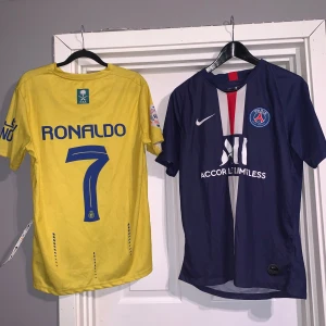 Al Nassr och PSG fotbollströjor - Två fotbollströjor: en gul Al Nassr-tröja med blå detaljer och Ronaldo 7 på ryggen, samt en blå PSG-tröja med röd och vit rand på framsidan och klubbmärke. Båda är kortärmade och har klassiska klubbtryck.