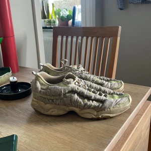 Beige sneakers från Acne Studios - Unika sneakers från Acne Studios i beige och ljusgrön färg med rynkad textil och snörning. Skorna har en chunky sula och detaljer i syntetmaterial. Från Acne Studios SS23. 