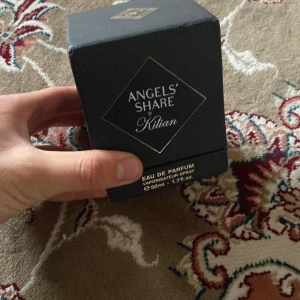 Angels' Share Eau de Parfum från Kilian - Exklusiv parfym från Kilian, Angels' Share, i en lyxig och tung glaskaraff med snidad design och gulddetaljer. Flaskan rymmer 50 ml och har en elegant, transparent look med guldmönstrad etikett. Doften är en Eau de Parfum och tillverkad i Frankrike.