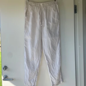 Beiga linnebyxor från H&M - Säljer ett par beiga linnebyxor från H&M med elastisk midja. Byxorna har raka ben och sidfickor, perfekta för en avslappnad stil. Luftiga och sköna i tunt linnematerial.