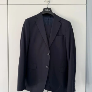 Mörkblå kostym från Oscar Jacobson - Säljer en klassisk mörkblå kostym från Oscar Jacobson. Använts ett fåtal gånger och är i mycket bra skick! 