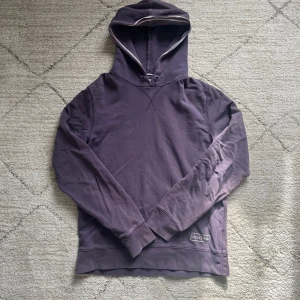 Lila hoodie från Marc O'Polo - Säljer en stilren lila hoodie från Marc O'Polo med broderad logga på ryggen. Tröjan har långa ärmar, huva och ribbade muddar. Perfekt för en avslappnad och trendig look.