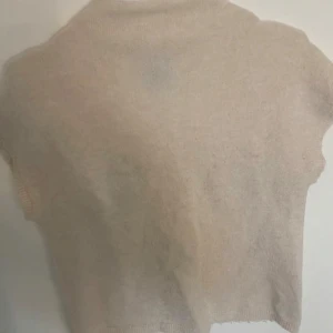 Beige stickad tröja från Lindex - Mysig beige stickad tröja från Lindex. Tröjan har en enkel design med korta ärmar och rak passform. Perfekt att styla med jeans eller kjol. Är lite nopprig men går att ta bort💗