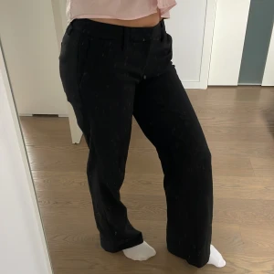 Low waist svarta kostymbyxor med raka ben - Säljer ett par skitcoola svarta kostymbyxor med raka ben och låg midja. Byxorna har gulliga detaljer som bakfickor med knapp. Bra längd på benen (jag är 168cm lång o de är nästan lite långa). Knappt använda, men köpta ett tag sedan