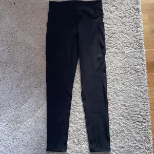 Svarta träningstights från H&M Move - Svarta träningstights från H&M Move med hög midja och praktisk ficka på sidan. Tightsen är stretchiga och sitter tight, perfekta för träning eller sport. Snygg och enkel design som passar till det mesta. Har inte använts. 