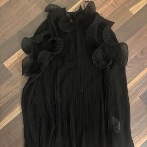 Svart volangblus från Zara XS - Säljer en svart blus från Zara i storlek XS. Blusen har transparent tyg, plisserade detaljer och stora volanger längs axlar och ärmar. 