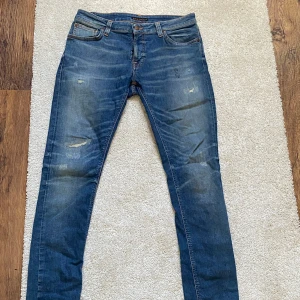  Nudie Jeans Authentic Repair - Säljer ett par blå skinny jeans från Nudie Jeans "Authentic Repair" med slitna detaljer och klassisk femficksdesign. Jeansen har mellanblå tvätt, orange sömmar och broderade bakfickor. Jeansen är i nyskick ( använda någon fåtal gång ) Nypris ligger på cirka 2500 Kr "slutsåld överallt"