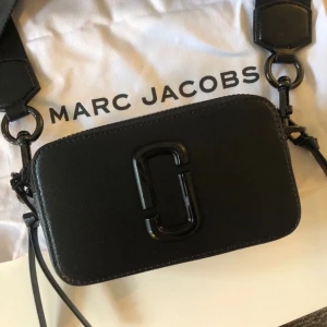 Marc Jacobs SNAPSHOT i läder - Äkta axelväska från Marc Jacobs i skinn med bred axelrem och dubbla dragkedjor. Perfekt storlek för mobil, plånbok och småprylar. Axelremmen kan justeras mycket. Sparsamt använd. Färg - Svart/svart 