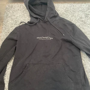 Svart hoodie Athletic Heritage League - Svart hoodie med tryck 'athletic heritage league North Western Division Est. 1979' på bröstet. Klassisk känguruficka framtill, huva med snörning och långa ärmar. Perfekt för en chill och sportig look.