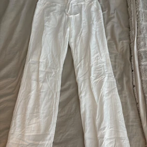Vita linnebyxor med snörning - Snygga och luftiga vita linnebyxor med raka ben och snörning i midjan. Byxorna har fickor framtill!