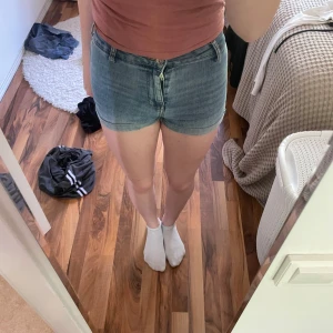 Ljusblå jeansshorts med hög midja - Snygga ljusblå jeansshorts med hög midja och klassisk femficksdesign. De har dragkedja och knapp framtill samt bälteshällor. Shortsen är tighta och har en kort passform, perfekta för varma sommardagar. Materialet är mjukt denim som ger en avslappnad vibe.