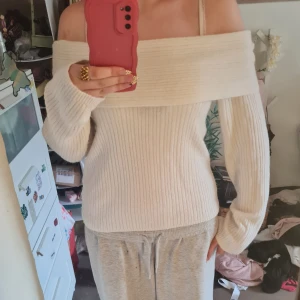 Offshoulder ribbad vit stickad tröja H&M - Superfin offshoulder tröja från H&M i ribbstickad modell. Tröjan är vit, har långa ärmar och bred krage som sitter snyggt över axlarna. Perfekt för dig som gillar en stilren och trendig look med lite extra edge.