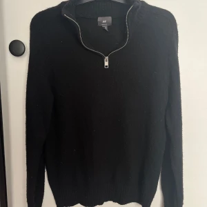 Svart stickad half zip-tröja H&M - Svart stickad tröja från H&M med half zip-dragkedja och hög krage. Regular fit och långa ärmar, perfekt för lager-på-lager. Enkel och stilren design som funkar till allt. Materialet är mjukt och ger en skön känsla hela dagen.