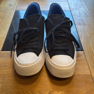 Svarta Converse sneakers med blå detaljer - Snygga svarta Converse sneakers med vit tå och sula, samt blå insida och coola detaljer på hälen. Skorna har snörning och är tillverkade i textil. Perfekta för dig som gillar en sportig och modern stil. Billigare vid snabba köp