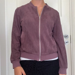 Lila mocka bomberjacka Broke+Schön - Säljer en snygg lila bomberjacka i mockaimitation från Broke+Schön. Jackan har silvrig dragkedja, ribbade muddar och klassisk bomberkrage. Perfekt för dig som vill ha en stilren och trendig jacka med mjuk känsla. Skriv om du undrar något, kolla min profil innan du trycker på köp nu💖💖