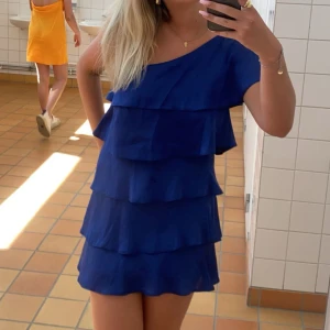 Blå volangklänning - Snygg blå kortklänning med flera volanglager och one shoulder-design. Köpt på plick för nått år sen och vet tyvärr inte märket på den, det står Atmosphere i den. Den är inte använd så mycket så den är i väldigt bra skick❤️