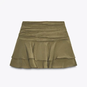 Olivgrön volangkjol  - Supersnygg olivgrön kortkjol med volanger. Kjolen har en omlottkänsla upptill och är perfekt för dig som vill ha en trendig och bekväm stil. Passar till både sneakers och boots. Aldrig använd
