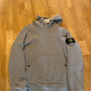 Grå hoodie från Stone Island - Säljer denna Stone Island hoodien i sjukt bra skick, endast använd ett fåtal gånger. Storlek M och äkta såklart. Pris kan diskuteras 
